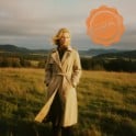 A sample picture of a girl in a trench coat standing in a meadow with an orange postmark